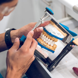 Dental technician holding artificial teeth on holder